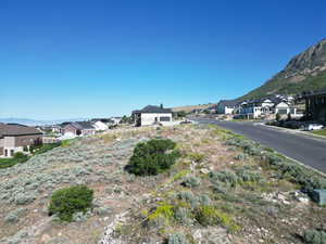 View of asphalt road featuring a residential view, a mountain view, and curbs