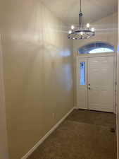 Foyer entrance with baseboards, dark carpet, a chandelier, and dark tile patterned flooring