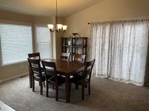 Dining room with carpet, baseboards, vaulted ceiling, and a notable chandelier