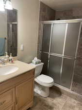 Full bathroom featuring toilet, a stall shower, and vanity