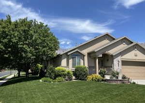 Ranch-style home with stucco siding, an attached garage, a front lawn, and concrete driveway