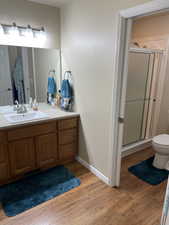 Full bathroom featuring visible vents, toilet, vanity, a shower stall, and wood finished floors
