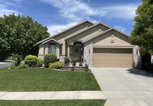 Ranch-style home featuring stucco siding, concrete driveway, a garage, a front lawn, and stone siding