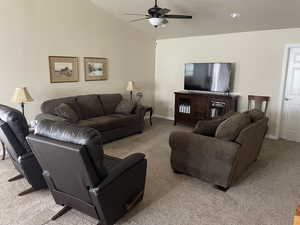 Living area with light carpet, lofted ceiling, a ceiling fan, and baseboards