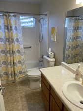 Bathroom with shower / bath combo with shower curtain, vanity, toilet, and tile patterned floors