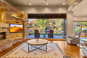 Living area featuring wood-type flooring, a stone fireplace, and recessed lighting