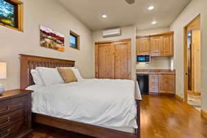 Bedroom with hardwood / wood-style flooring, recessed lighting, an AC wall unit, and fridge