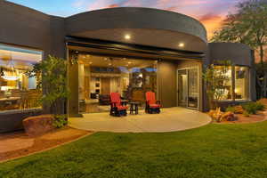 Back of property featuring a patio area, a lawn, and stucco siding