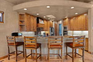 Kitchen with premium range hood, appliances with stainless steel finishes, a peninsula, recessed lighting, and open shelves