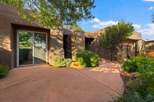 View of front of house with a patio area, stucco siding, and stone siding
