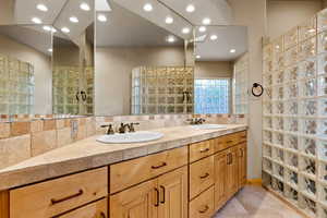 Bathroom featuring double vanity, tile patterned floors, tasteful backsplash, recessed lighting, and a walk in shower