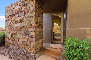 Entrance to property featuring stone siding and stucco siding