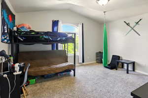 Carpeted bedroom featuring lofted ceiling and baseboards