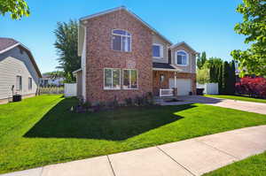 Traditional-style home featuring an attached garage, driveway, brick siding, and central AC unit