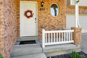 Property entrance featuring brick siding and a porch
