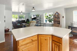 Kitchen with dark wood-style floors, open floor plan, light countertops, and a center island