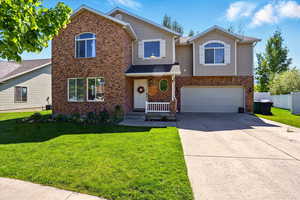 Traditional-style home with driveway, an attached garage, and brick siding