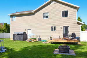Rear view of property featuring an outdoor fire pit and a wooden deck