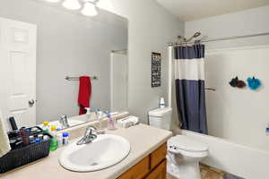 Bathroom featuring vanity, shower / tub combo, and toilet