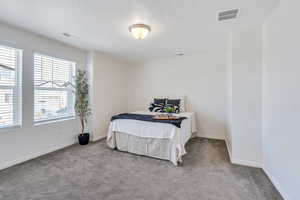 Carpeted bedroom featuring baseboards and a textured ceiling