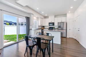 Kitchen with black appliances, a kitchen island, dark wood finished floors, white cabinets, and a sink