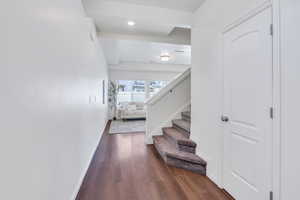 Hall with dark wood-style floors, stairs, baseboards, and recessed lighting