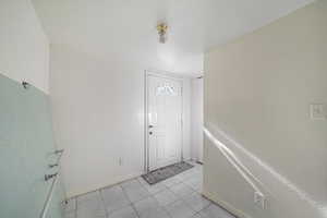 Foyer entrance with light tile patterned floors and baseboards