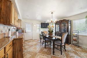 Dining space with a chandelier, baseboards, light tile patterned floors, and a textured ceiling