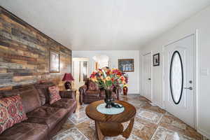 Foyer with wooden walls, an accent wall, arched walkways, baseboards, and light stone finish flooring