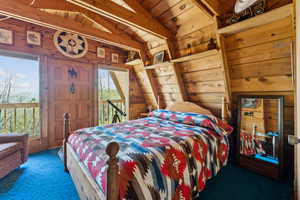 Bedroom featuring carpet flooring, multiple windows, wooden ceiling, and wooden walls
