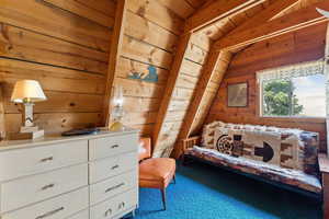 Bedroom with wooden walls and vaulted ceiling