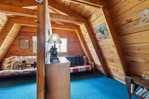 Hall featuring wooden walls, carpet floors, and wood ceiling