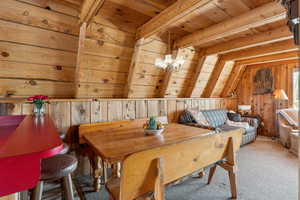 Dining space featuring wooden ceiling, wood walls, carpet, and a chandelier