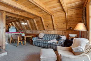 Living room featuring wooden ceiling, carpet floors, wooden walls, and a chandelier