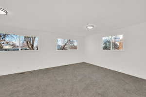 Spare room featuring plenty of natural light, dark colored carpet, and baseboards