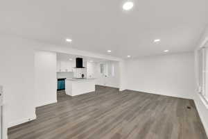 Unfurnished living room with recessed lighting, dark wood-style floors, and baseboards