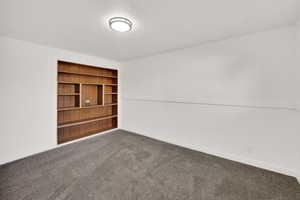 Empty room featuring dark carpet and baseboards