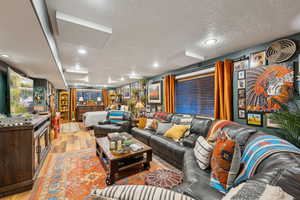 Living room with light wood finished floors, recessed lighting, and a textured ceiling