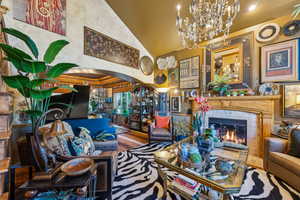 Living area featuring a chandelier, arched walkways, a high end fireplace, and high vaulted ceiling