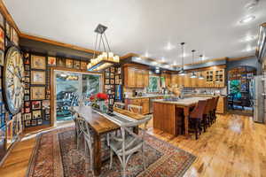 Dining area featuring crown molding, light wood finished floors, arched walkways, and recessed lighting