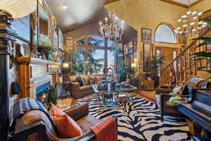 Living room featuring a chandelier, high vaulted ceiling, stairway, and a tiled fireplace