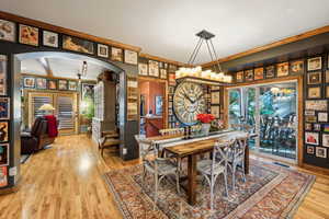 Dining area featuring arched walkways, wood finished floors, and crown molding