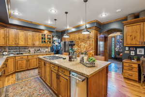 Kitchen featuring arched walkways, ornamental molding, stainless steel gas cooktop, a center island, and backsplash