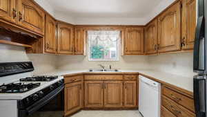 Kitchen featuring range with gas stovetop, white dishwasher, brown cabinets, and a sink