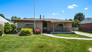 View of front facade with a porch, a front yard, and roof with shingles