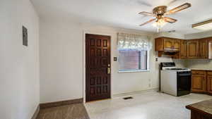 Kitchen with range with gas cooktop, a ceiling fan, brown cabinets, and baseboards