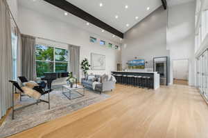 Living room featuring high vaulted ceiling, beam ceiling, light wood finished floors, wine cooler, and recessed lighting