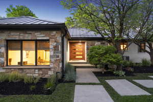 View of front of house with a standing seam roof, stone siding, metal roof, and a fireplace