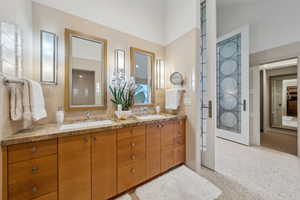 Full bath with double vanity, speckle patterned floor, and tile walls