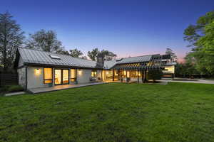 Rear view of house featuring a standing seam roof, metal roof, and a chimney